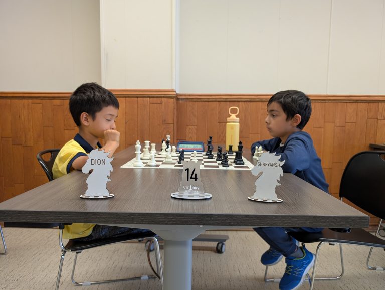 Young players facing each other across the chessboard