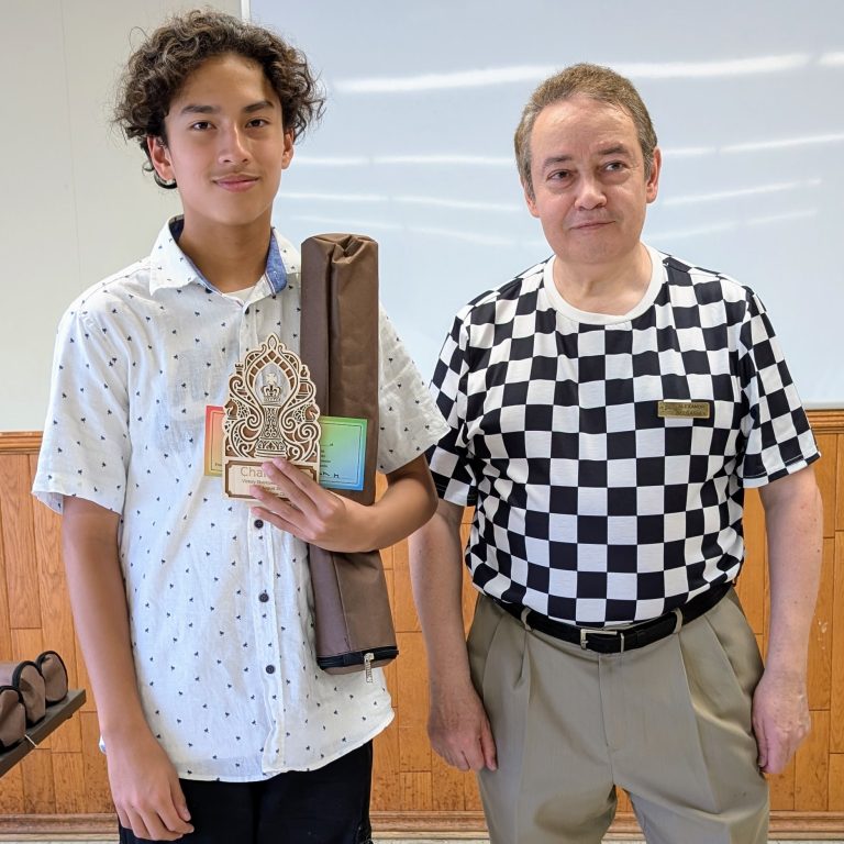 A tournament champion receiving his trophy from FM Alexandr Delgashev